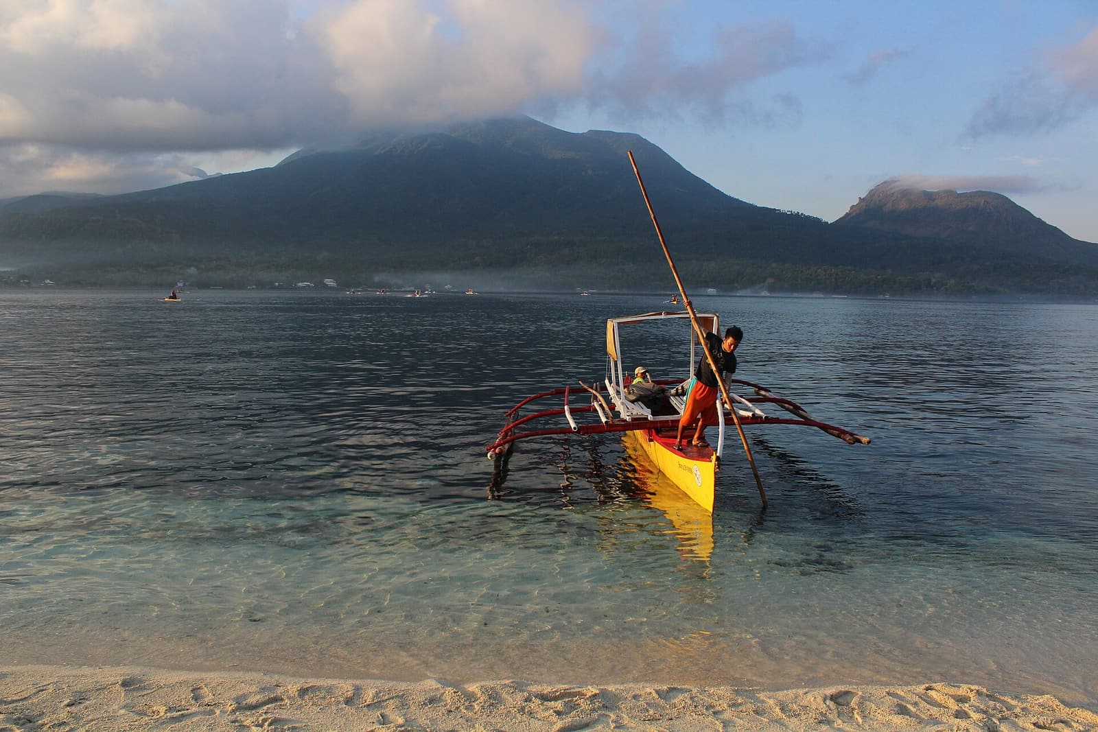 An outrigger bangka being brought to shore off Camiguin, with Mount Hibok-Hibok behind