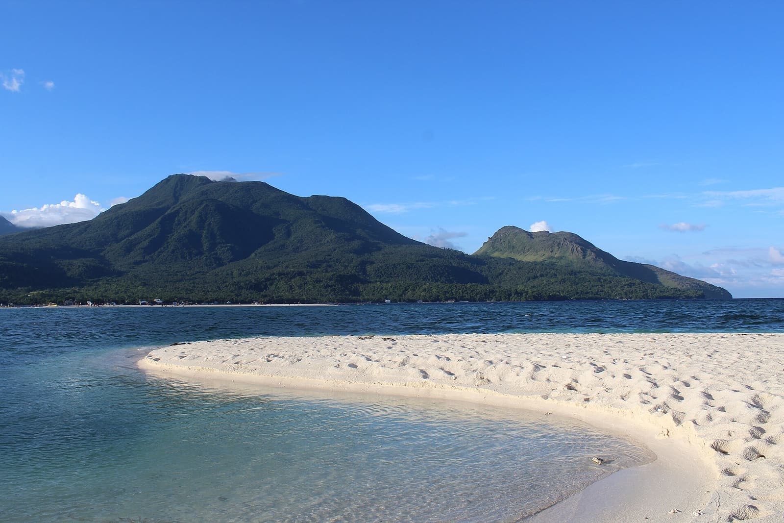 The bare white sandbar of White Island surrounded by turquoise water, with Camiguin’s volcanoes behind