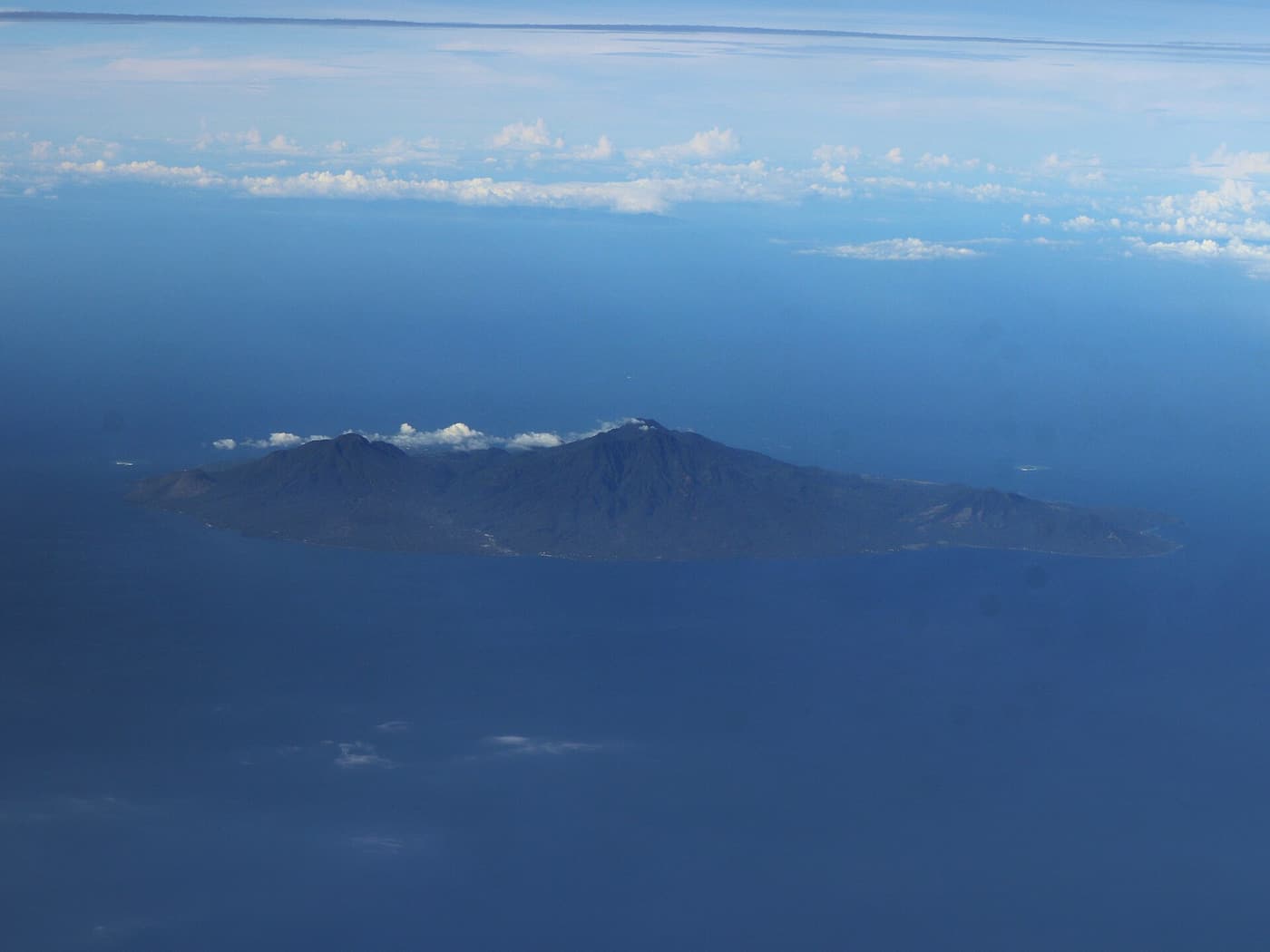 Camiguin seen from the air, a green volcanic island in a deep-blue sea