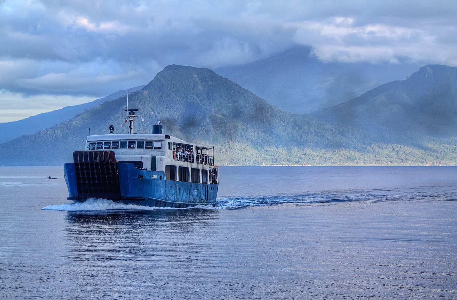 A passenger ferry crossing calm water towards Camiguin’s volcanic peaks