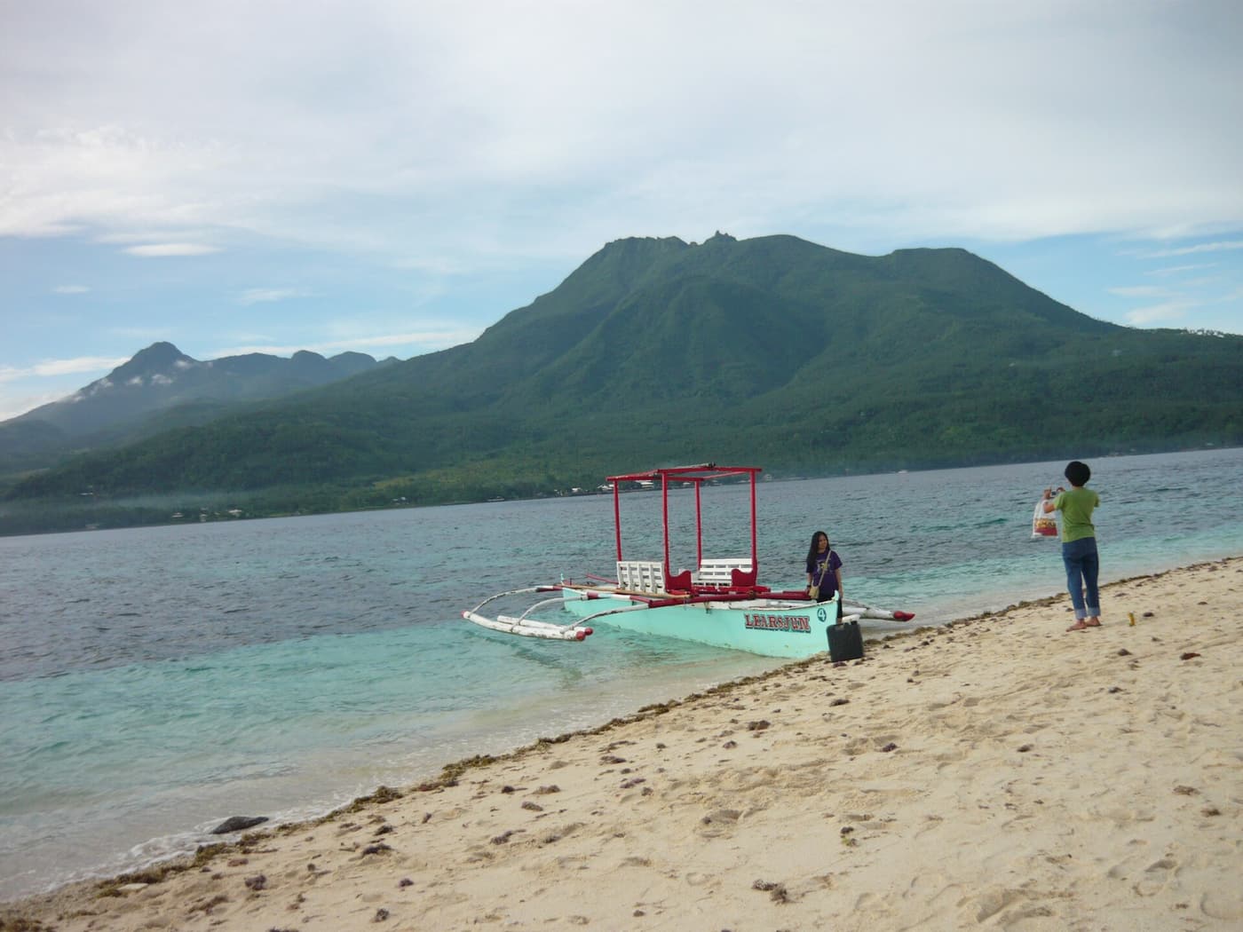 A beach on Camiguin with a moored outrigger boat and the volcano behind